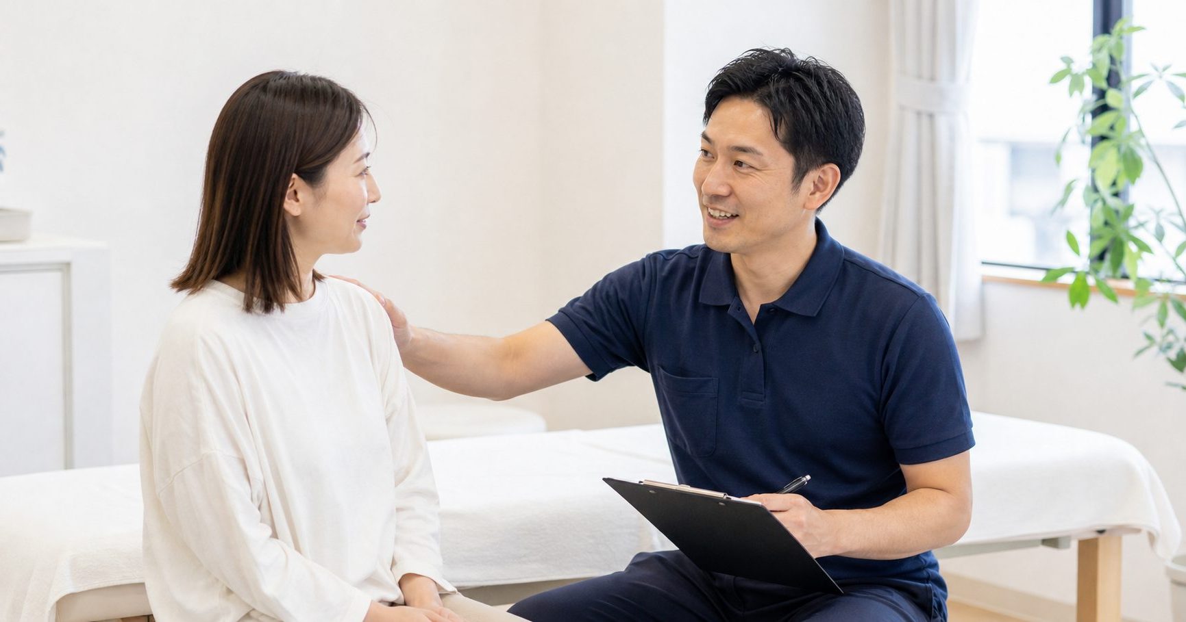 施術ベッドのそばで、体の状態を伺いながらお話しするカウンセリングの様子